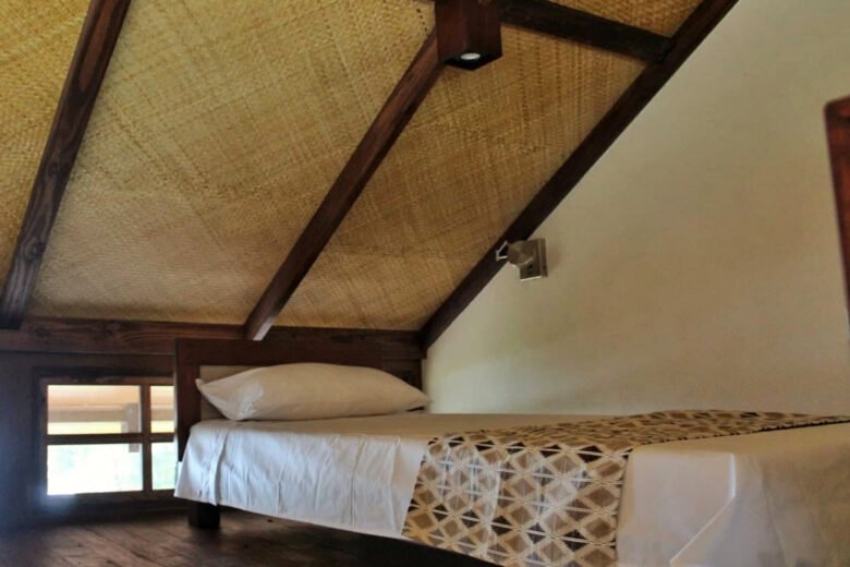 Cozy villa bedroom with rustic wooden bed and thatched ceiling at Villas Azul Ballena, Uvita.
