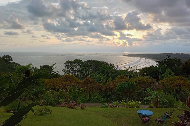 Panoramic ocean view at dusk from Villas Azul Ballena with lush garden in the foreground.